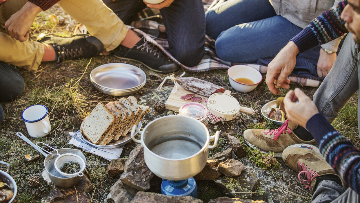  Friends preparing breakfast at campsite. 