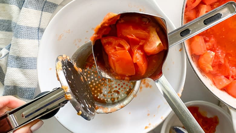 Top-down view of tomatoes going into a potato ricer