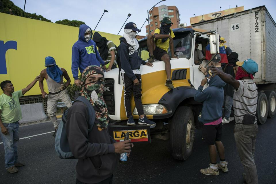 Anti-government protesters stop a truck while blocking a highway with a small group of demonstrators who were returning from a peaceful demonstration called by self-declared interim president Juan Guaido to demand the resignation of President Nicolas Maduro, in Caracas, Venezuela, Saturday, Feb. 2, 2019. (AP Photo/Rodrigo Abd)