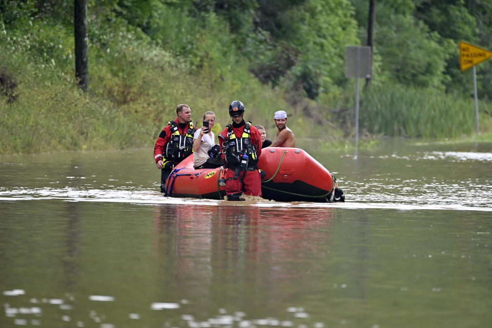 Members of the Winchester, Ky., Fire Department walk inflatable boats across flood waters over Ky. State Road 15 in Jackson, Ky., to pick up people stranded by the floodwaters Thursday, July 28, 2022. Flash flooding and mudslides were reported across the mountainous region of eastern Kentucky, where thunderstorms have dumped several inches of rain over the past few days. (AP Photo/Timothy D. Easley)