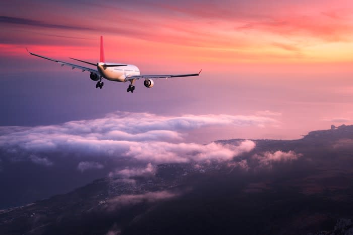 A plane lands in a coastal city at sunset.