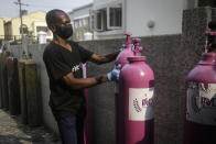 A worker from a private medical service brings oxygen bottles to aid the recovery of a COVID-19 patient, at her home in Lagos, Nigeria on Saturday, Feb. 6, 2021. A crisis over the supply of medical oxygen for coronavirus patients has struck nations in Africa and Latin America, where warnings went unheeded at the start of the pandemic and doctors say the shortage has led to unnecessary deaths. (AP Photo/Sunday Alamba)