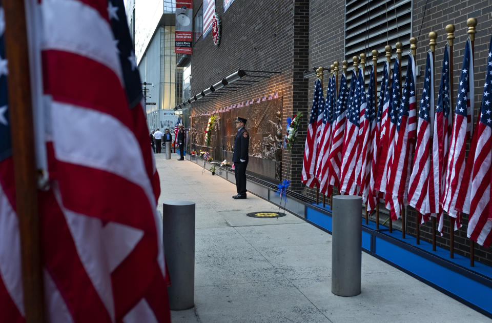 New York City firefighters stand at attention in front of a memorial on the side of a firehouse adjacent to One World Trade Center and the 9/11 Memorial site during ceremonies commemorating the 18th anniversary of the 9/11 terrorist attacks in New York on Wednesday, Sept. 11, 2019. (AP Photo/Craig Ruttle)