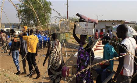 Displaced people walk past razor wire at Tomping camp, where some 15,000 displaced people who fled their homes are sheltered by the United Nations, near Juba January 7, 2014. REUTERS/James Akena