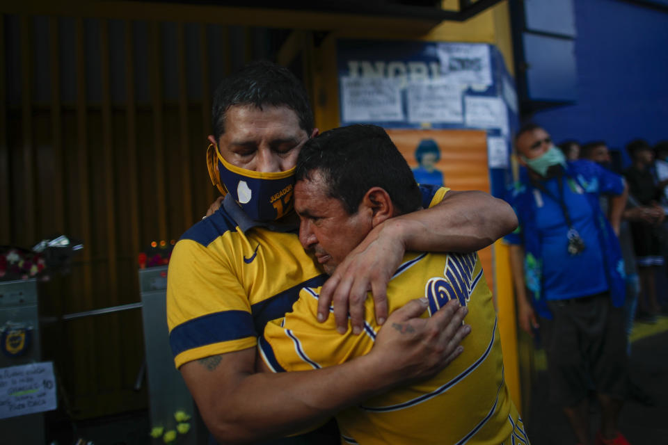 Fans mourn the death of Diego Maradona at the entrance of the Boca Juniors stadium, known as La Bombomera, in Buenos Aires, Argentina, Wednesday, Nov. 25, 2020. The Argentine soccer great who was among the best players ever and who led his country to the 1986 World Cup title before later struggling with cocaine use and obesity, died from a heart attack on Wednesday at his home in Buenos Aires. He was 60. (AP Photo/Natacha Pisarenko)