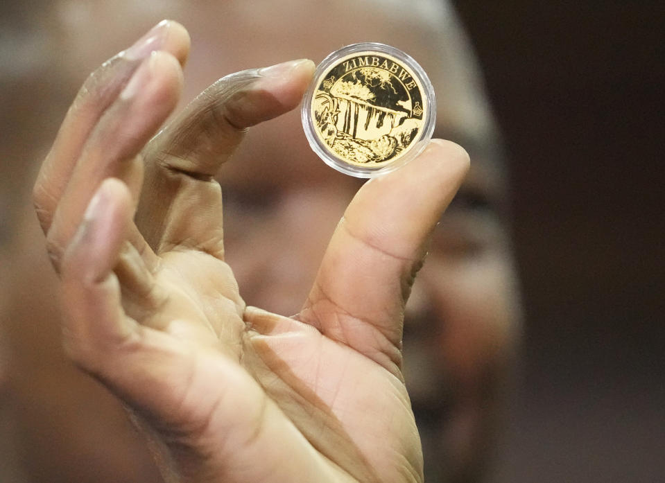 Reserve Bank of Zimbabwe Governor, John Mangudya holds a sample of a gold coin at the launch in Harare, Monday, July, 25, 2022. Zimbabwe has launched gold coins to be sold to the public in a bid to to tame runaway inflation that that has further eroded the country's unstable currency. (AP Photo/Tsvangirayi Mukwazhi)