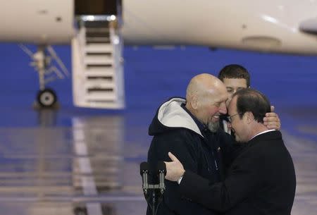 French President Francois Hollande (R) and former hostage Serge Lazarevic hug each other after delivering speeches at the Villacoublay military airport, near Paris, December 10, 2014. REUTERS/Jacky Naegelen