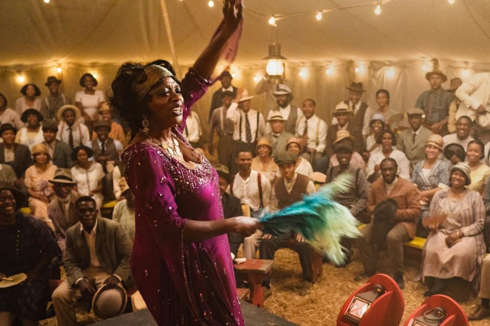 A woman stands onstage in front of a crowd.