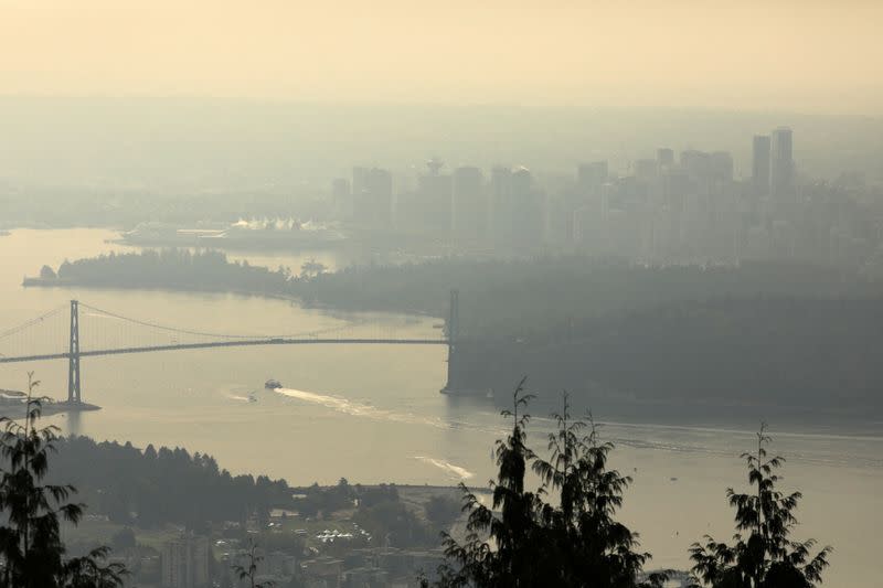 A boat passes under the Lions Gate bridge to enter Vancouver Harbour, shrouded in a haze a wildfire smoke