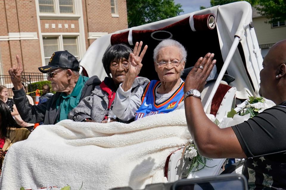 In this May 28, 2021, photo, Tulsa Race Massacre survivors, from left, Hughes Van Ellis Sr., Lessie Benningfield Randle, and Viola Fletcher, wave and high-five supporters from a horse-drawn carriage before a march in Tulsa.