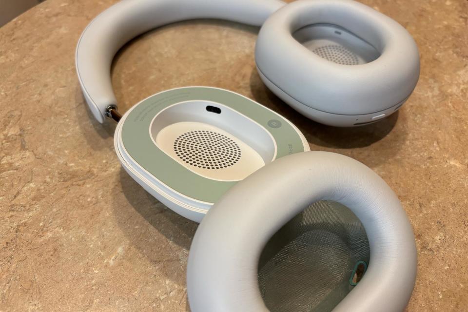 <p>White headphones laying flat on a small table, one ear pad removed.</p>
