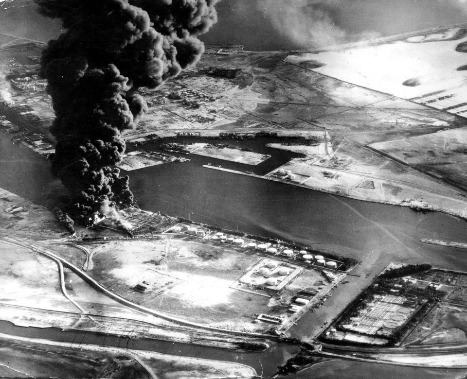 FILE - In this Nov. 11, 1956 file photo, fuel installations on the Suez Canal burn after an attack by aircraft of the Sea Venom Squadron from HMS Eagle as Britain, France and Israel intervened militarily and occupied the canal zone following Egypt nationalizing the canal. Since it opened in 1869, the canal has been a source of national pride and a focus of international conflict. Now, a skyscraper-sized container ship called the Ever Given got stuck sideways across the waterway since Tuesday, March 23, 2021 . The obstruction has halted canal traffic, valued at over $9 billion a day. (AP Photo, File)