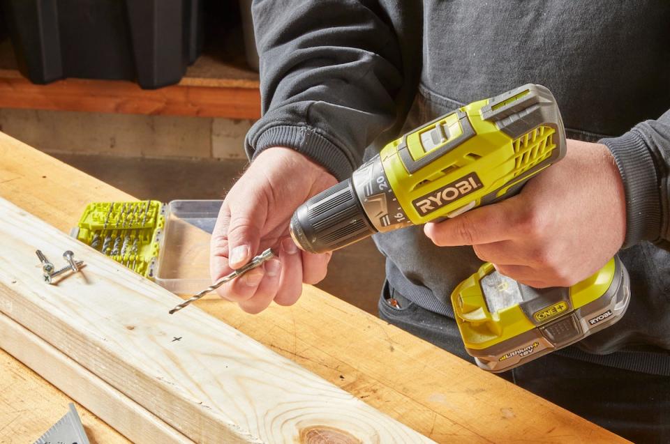 Man fits a drill bit into a drill. 