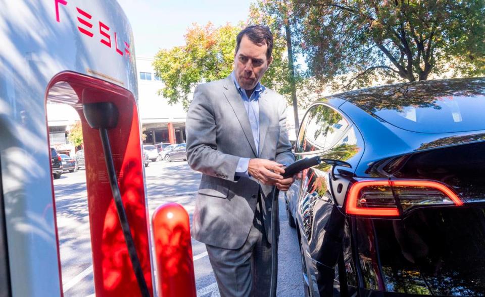 Aaron Landry of Pinehurst finishes charging his Model Y Tesla at an electric charging station at North Hills in Raleigh Tuesday, October. 17, 2023. Electric vehicle owners will see an increase in both new vehicle and annual registration fees.