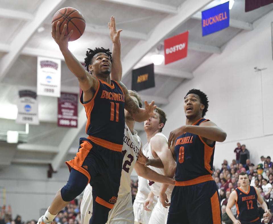 Bucknell guard Avi Toomer, left, drives for a layup past Colgate center Dana Batt as Bucknell center Paul Newman (0) watches during the first half of an NCAA college basketball game for the championship of the Patriot League men's tournament in Hamilton, N.Y., Wednesday, March 13, 2019. (AP Photo/Adrian Kraus)