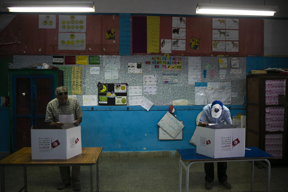 Voters cast their ballot inside a polling station during a parliamentary election in La Marsa, outside Tunis, Tunisia, Sunday, Oct. 6, 2019. Tunisians were electing a new parliament Sunday amid a tumultuous political season, with a moderate Islamist party and a jailed tycoon's populist movement vying to come out on top of a crowded field. (AP Photo/Riadh Dridi)
