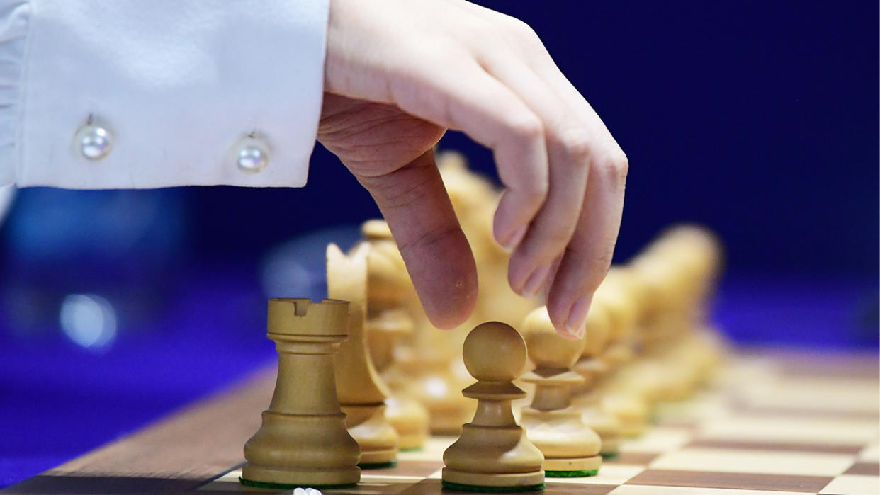 A player is pictured moving a chess piece during the 2020 FIDE Women's World Chess Championship .