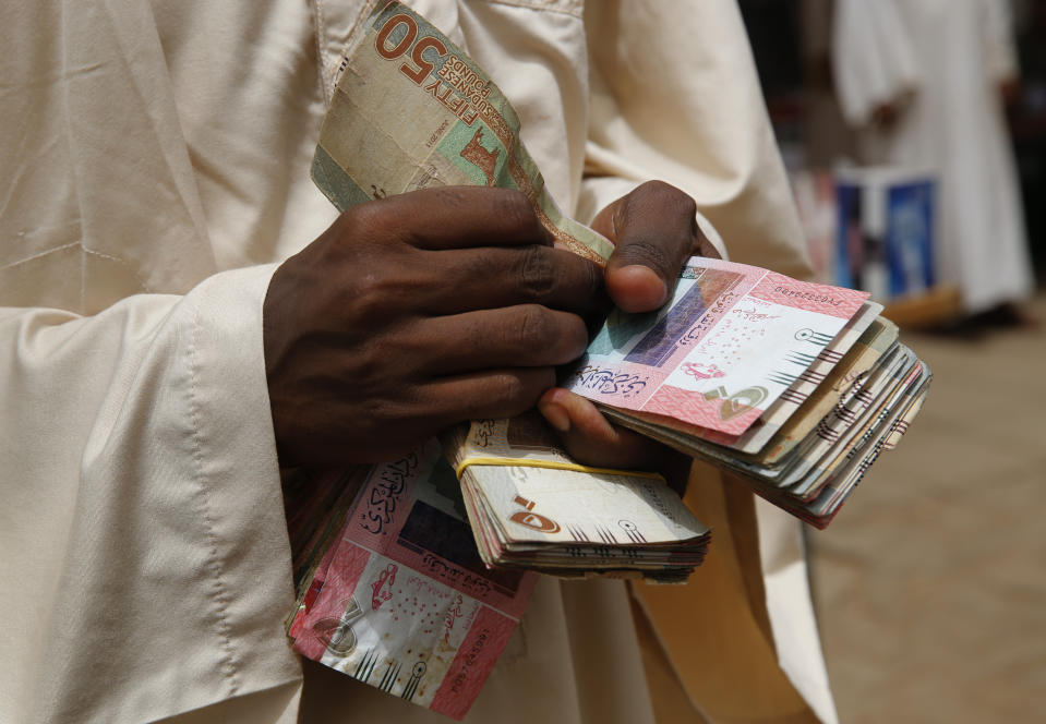 A money exchanger counts money at a popular market, in Khartoum, Sudan, Monday, June 24, 2019. Sudan's protest movement accepted an Ethiopian roadmap for a civilian-led transitional government, a spokesman said on Sunday, after a months-long standoff with the country's military rulers — who did not immediately commit to the plan. (AP Photo/Hussein Malla)