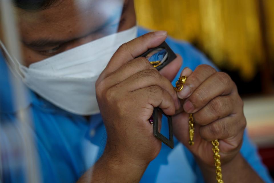 A gold seller examines golden ornaments before trading at a gold shop in Chinatown, Bangkok, Thailand, 10 March 2022.