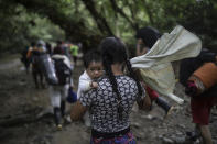 A Bolivian migrant carrying a baby walks across the Darien Gap from Colombia to Panama in hopes of reaching the U.S., Tuesday, May 9, 2023. Pandemic-related U.S. asylum restrictions, known as Title 42, are to expire Thursday, May 11. (AP Photo/Ivan Valencia)