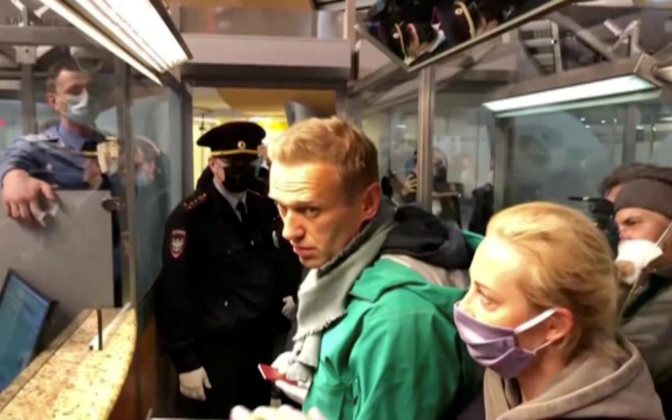 A still image taken from video footage shows law enforcement officers speaking with Alexei Navalny before leading him away - Reuters