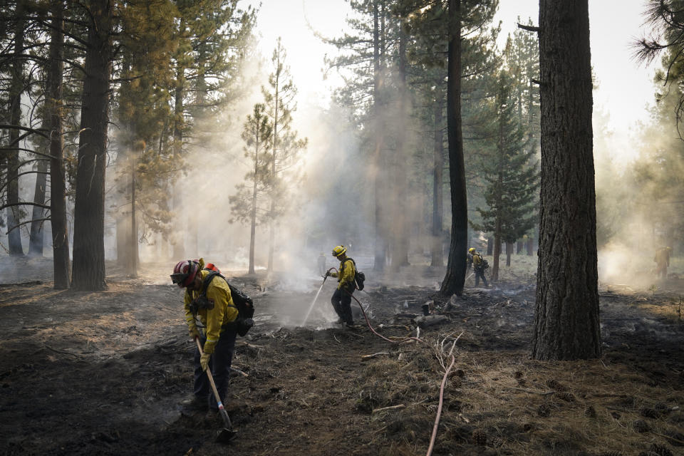 Firefighters put out hot spots near South Lake Tahoe, Calif., Wednesday, Sept. 1, 2021. Authorities are reporting progress in the battle to save communities on the south end of Lake Tahoe from a huge forest fire. (AP Photo/Jae C. Hong)