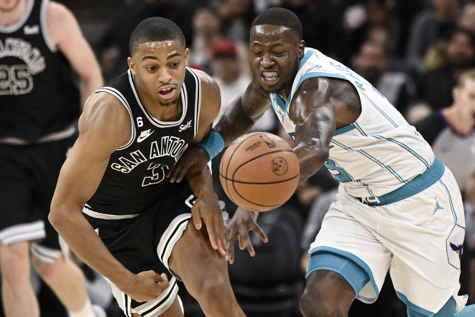 Charlotte Hornets' Terry Rozier, right, and San Antonio Spurs' Keldon Johnson vie for possession of the ball during the first half of an NBA basketball game Wednesday, Oct. 19, 2022, in San Antonio. (AP Photo/Darren Abate)