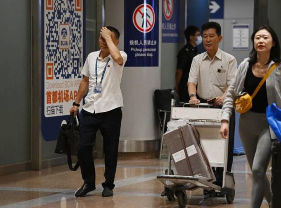 Two North Korean men (L and 2nd R) walk through the arrivals section at Beijing Capital Airport after the arrival of Air Koryo flight JS151 on 22 August 2023 (AFP via Getty Images)