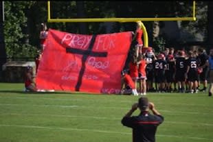 Jon Ross Snell's teammates run through a pregame sign honoring their sick teammate — Caring Bridge