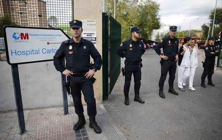 Police stand at the entrance of the Carlos III hospital, where a nurse who contracted Ebola is being treated, during a demonstration against government spending cuts in the health care sector, in Madrid October 8, 2014. REUTERS/Paul Hanna