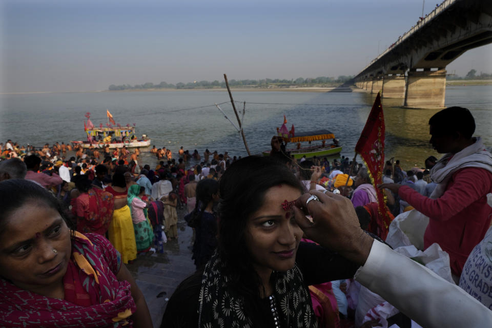 A Hindu priest applies vermilion on the forehead of girl on the bank of the river Saryu on the occasion of Ramnavi festival, celebrated as the birthday of Hindu god Ram, in Ayodhya, India, March 30, 2023. India is on the cusp to eclipse China as the world's most populated country, but its religious fault lines have become starker, a testament to the perils of rising Hindu nationalism in a constitutionally secular country. (AP Photo/Manish Swarup)