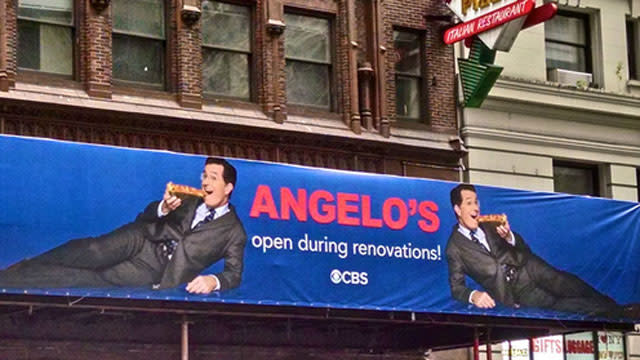 Those walking past New York City's Ed Sullivan Theater got a slice of comedy thanks to Stephen Colbert's temporary <em>Late Show</em> marquee. In anticipation of Colbert's debut on the late-night CBS program, a sign was put up to promote Angelo's Pizza, which is located next door to the studio. <strong> WATCH: Stephen Colbert Responds to Gwen Stefani Flubbing His Name </strong> The ad shows Colbert eating pizza with the message: "Angelo's open during renovations." ETONLINE Talk about prime ad space! This is after all the marquee location that once announced The Beatles first televised American appearance. . This is just one of many stunts Colbert has pulled off in lead-up to his new hosting gig. Just last week, he hosted a public access show in Monroe, Mich. and interviewed rapper Eminem. <strong> WATCH: Stephen Colbert Attempts a New <em>Late Show</em> Theme Song </strong> Also last month, Colbert nailed an impersonation of country crooner Toby Keith at the Songwriters Hall of Fame. The <em>Late Show with Stephen Colbert</em> premieres September 8. In the meantime, relive some of the best moments from David Letterman's last <em>Late Show:</em>