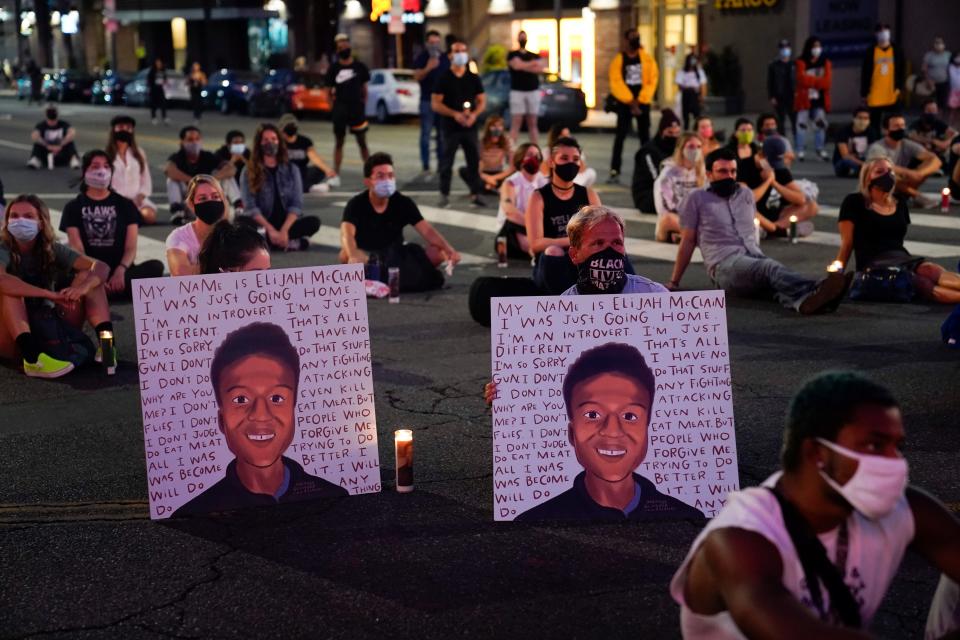 In this Aug. 24, 2020, file photo, two people hold posters showing images depicting Elijah McClain during a candlelight vigil for McClain outside the Laugh Factory in Los Angeles. An investigation into the arrest of McClain in suburban Denver criticizes how police handled the entire incident, faulting officers for their quick, aggressive treatment of the 23-year-old unarmed Black man and department overall for having a weak accountability system.
