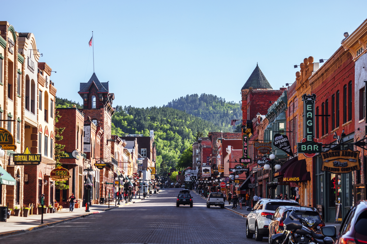 Historical town of Deadwood, South Dakota, buildings on both sides of the road, trees on mountains in the background