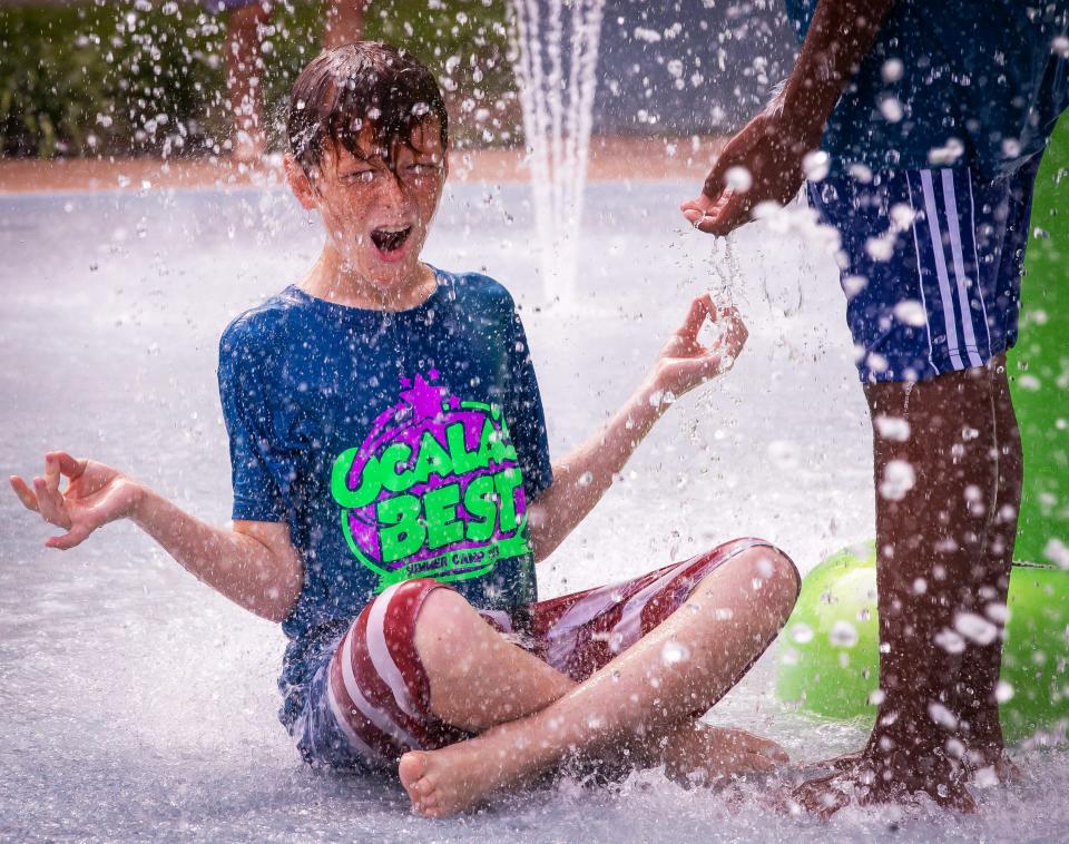 Dylan Grosz, 11, sits in his best Yoga pose as water splashes around him as children from Ocala's Best Summer Camp were trying to beat the heat Monday July 10, 2023 by playing at Lily's Pad, a splash pad located at Lillian Bryant Park. The park also offers basketball courts, a covered pavilion with picnic tables, a playground, walking trail and a little league baseball field.