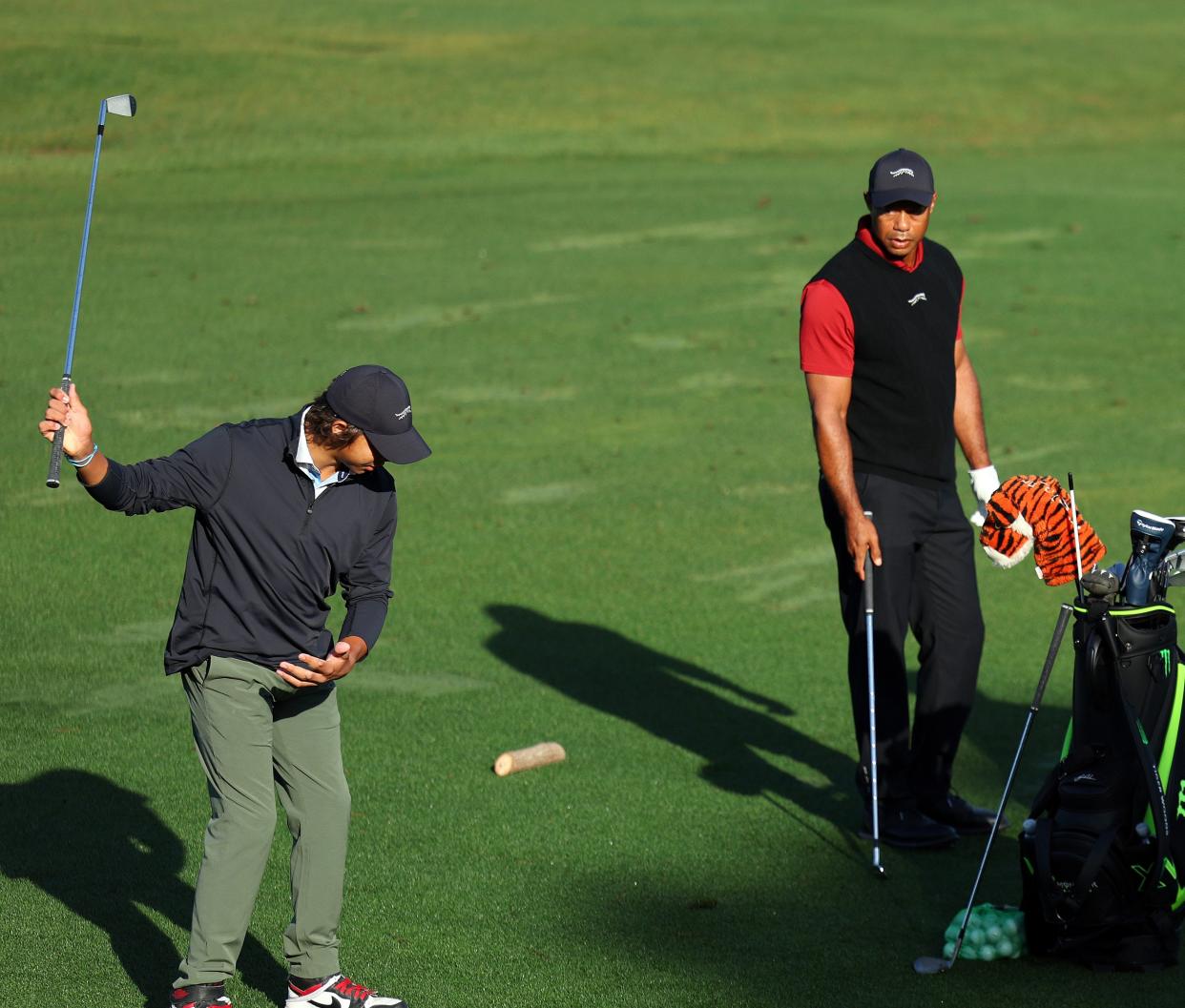 AUGUSTA, GEORGIA - APRIL 14: Tiger Woods of the United States warms up in the practice area as his caddie Lance Bennett and son Charlie Woods looks on during the final round of the 2024 Masters Tournament at Augusta National Golf Club on April 14, 2024 in Augusta, Georgia. (Photo by Andrew Redington/Getty Images) ORG XMIT: 776127404 ORIG FILE ID: 2148599174