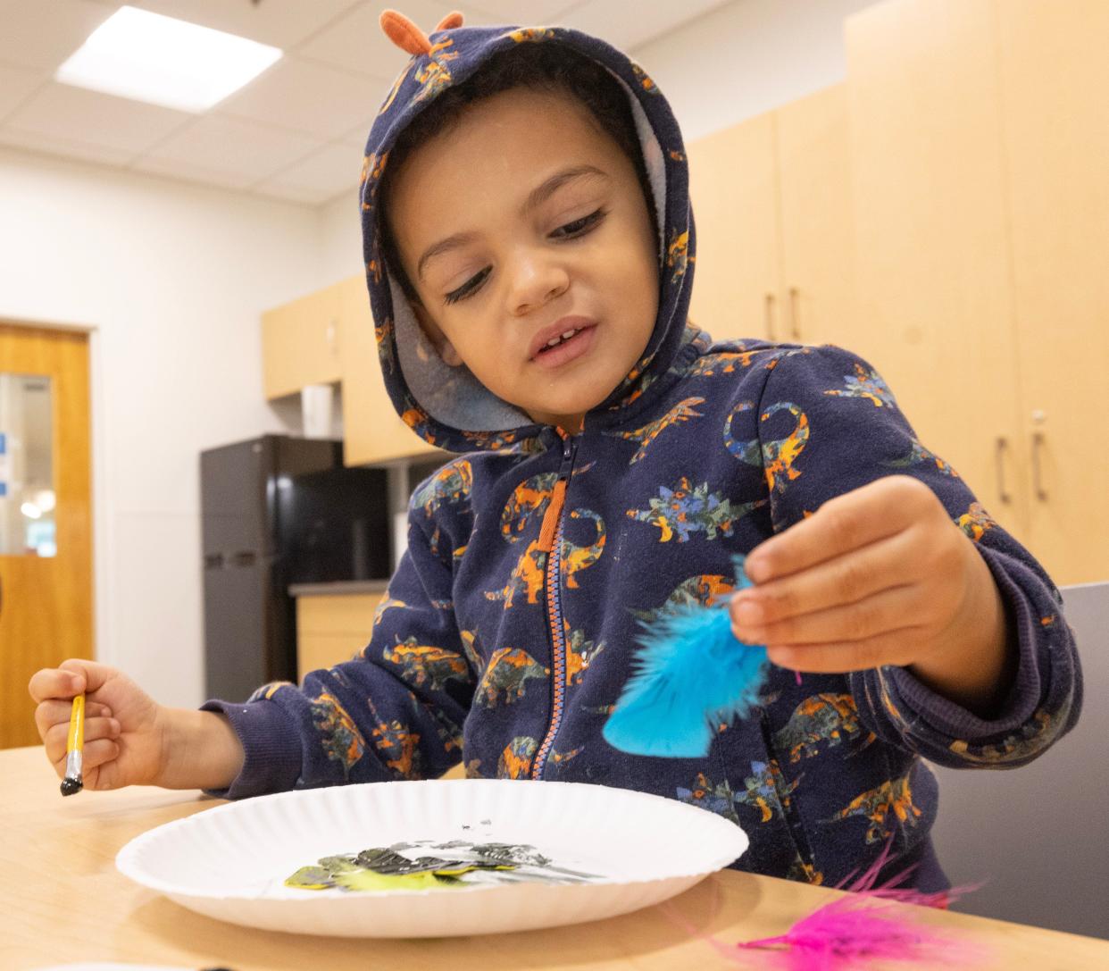 Andres Gisper, 3, uses feathers to paint patterns at the Perry Sippo Branch Library's Trail Tales/Arctic Animal Legends story and a craft program.