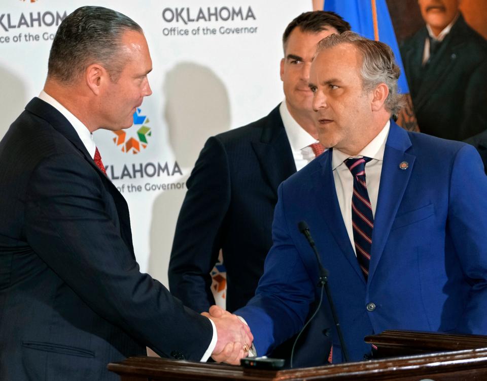 House Speaker Charles McCall and Senate President Pro Tem Greg Treat shake hands as Gov. Kevin Stitt looks on after major education funding agreement in 2023.