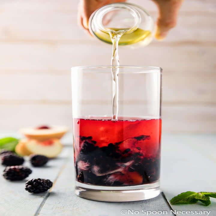 Pouring simple syrup into a cocktail.