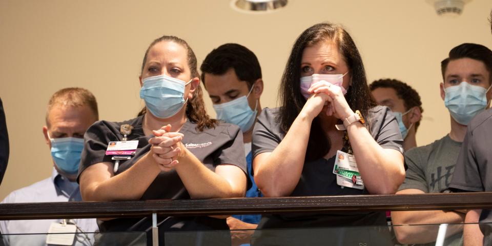 Saint Francis Hospital employees stand and listen to a press conference.