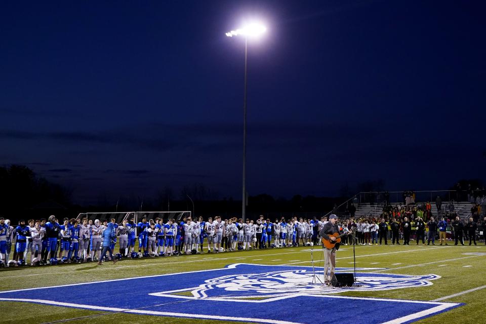 Singer James Taylor sings the national anthem as Lewiston High School and Edward Little High School players stand together, Wednesday, Nov. 1, 2023, prior to a high school football game in Lewiston, Maine. Locals seek a return to normalcy after a mass shooting on Oct. 25. (AP Photo/Matt York)