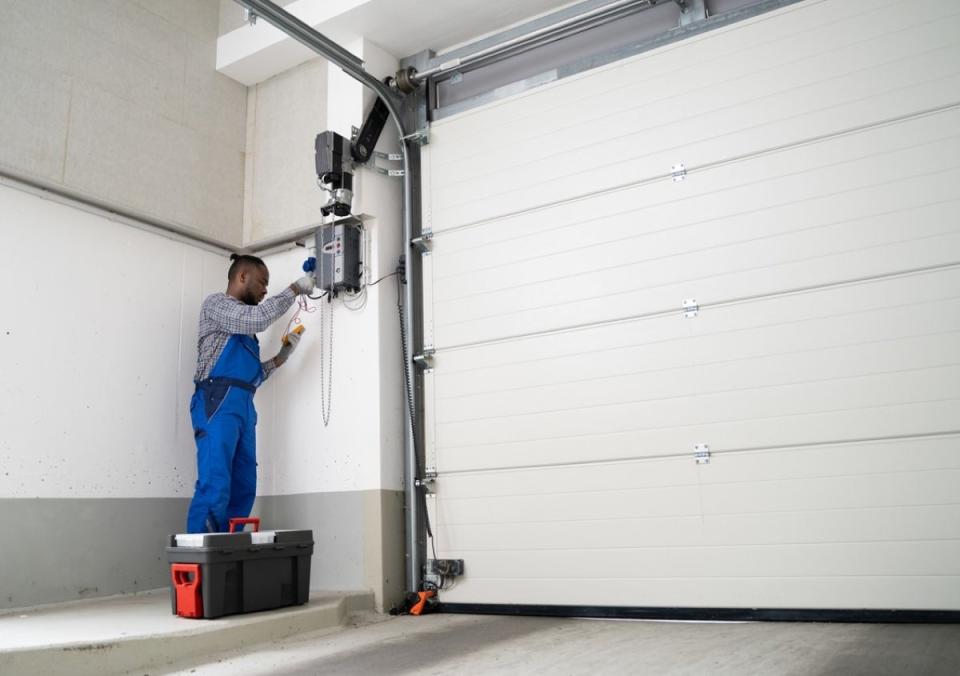 Professional repair man fixing a garage door spring.