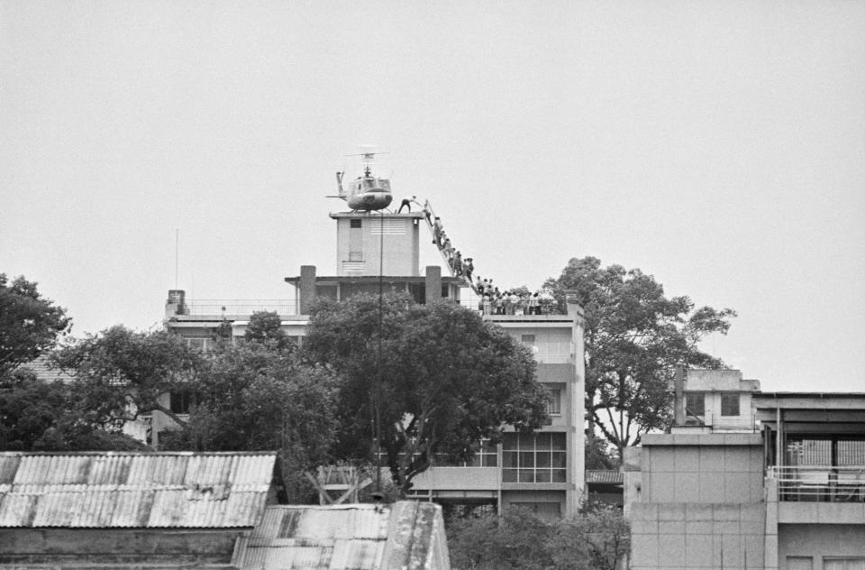 A CIA employee helps Vietnamese evacuees onto a helicopter from the top of a building near the U.S. Embassy in Saigon, April 1975. (Photo: AP)