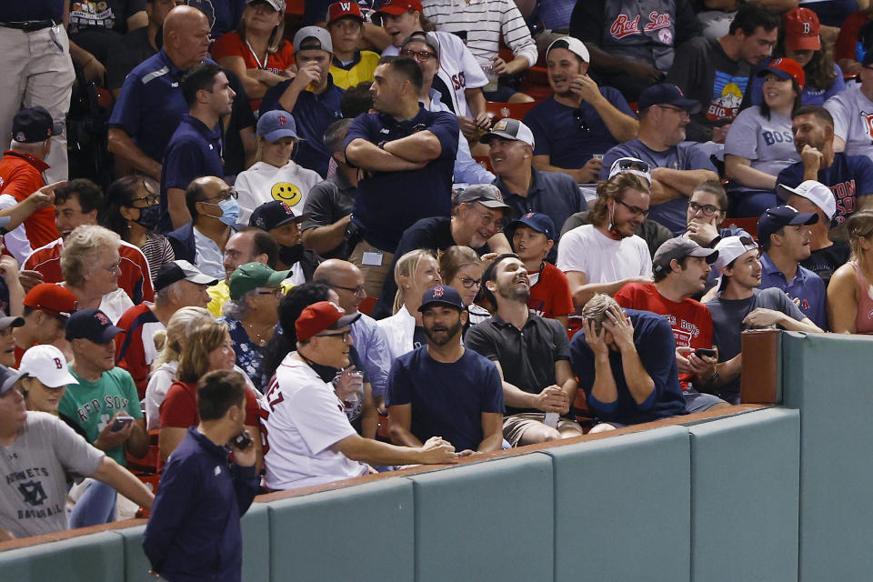 Security begins to move in to eject a fan, front row, holding head in hands, for interfering with Boston Red Sox's Danny Santana, who was trying to catch a foul ball during the fifth inning of the team's baseball game against the Tampa Bay Rays on Wednesday, Sept. 8, 2021, at Fenway Park in Boston. (AP Photo/Winslow Townson)