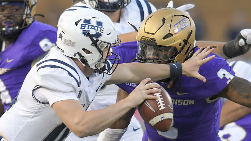 Utah State quarterback McCae Hillstead, front left, tries to scramble away from James Madison defensive lineman Mikail Kamara (3) during the first half of an NCAA college football game Saturday, Sept. 23, 2023, in Logan, Utah. 