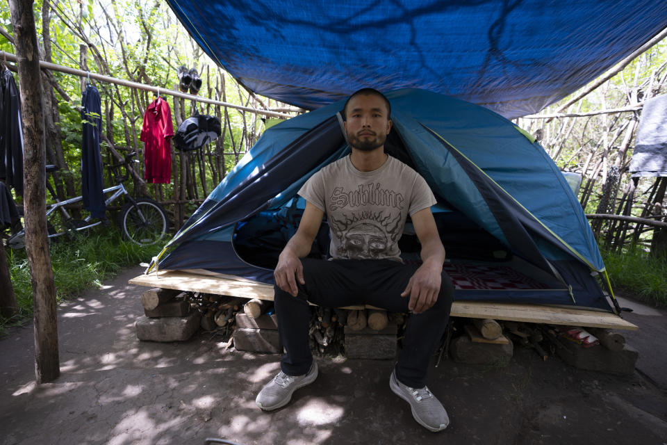 Chen Wang, un migrante chino que se encuentra actualmente sin hogar en Nueva York, posa para una foto delante de su casa de campaña el viernes 3 de mayo de 2024. (AP Foto/Serkan Gurbuz)