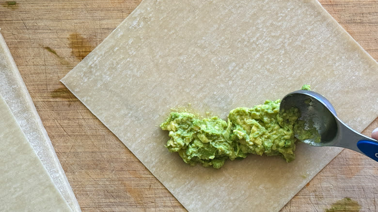 spoon adding avocado to wrapper