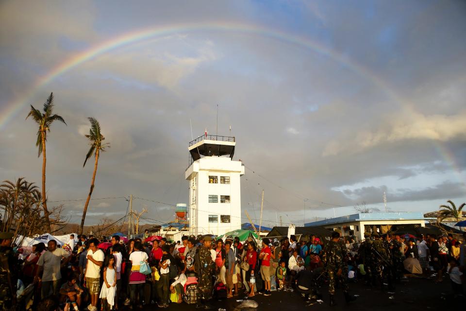 REFILE - QUALITY REPEAT A rainbow appears above typhoon survivors desperate to catch a military mercy flight, in the aftermath of the Super Typhoon Haiyan, at Tacloban airport, in central Philippines, November 15, 2013. The death toll from the powerful typhoon that swept the central Philippines nearly doubled overnight, reaching 4,000, as helicopters from a U.S. aircraft carrier and other naval ships began flying food, water and medical teams to ravaged regions. REUTERS/Erik De Castro (PHILIPPINES - Tags: DISASTER ENVIRONMENT TRANSPORT SOCIETY MILITARY)