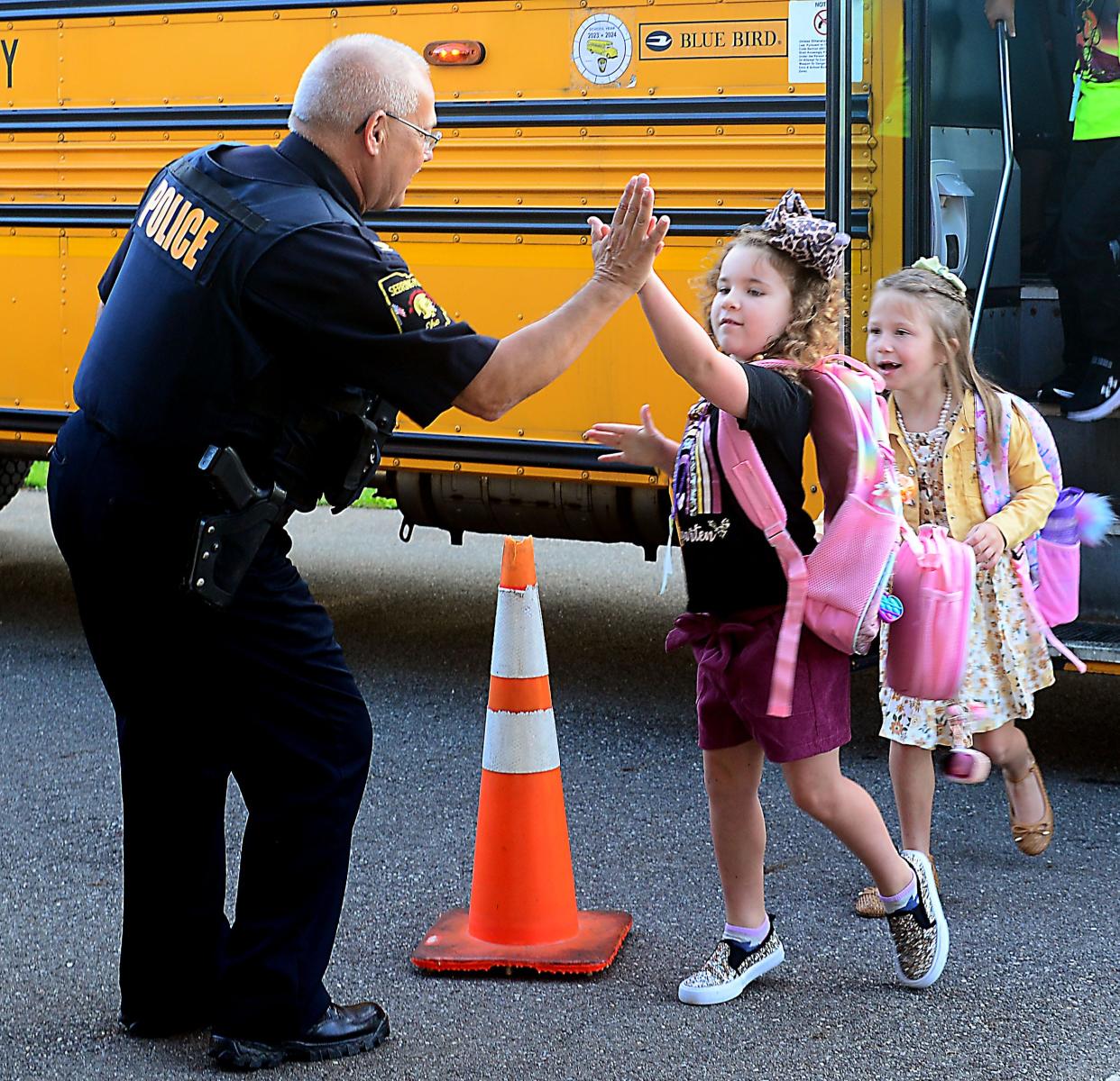 Sebring Police Chief Ray Harris welcomes Emory Armstrong with a high-five on the first day of school at B.L. Miller Elementary School on Thursday, Aug. 17, 2023.  Also pictured is Khaleesi Guy.