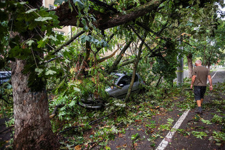 A man walks near a car that was hit by a falling tree following a storm that tore through western Romania, in Timisoara, Romania September 17, 2017. Inquam Photos/Cornel Putan Alin/via REUTERS